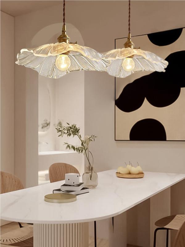Two wide clear lotus pendants above a dining table