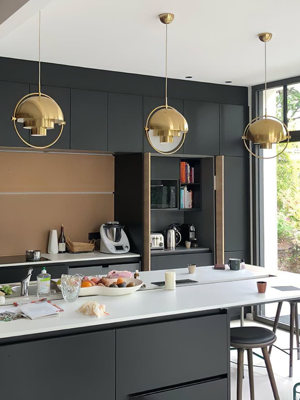 Three copper-finish pendants across a kitchen island