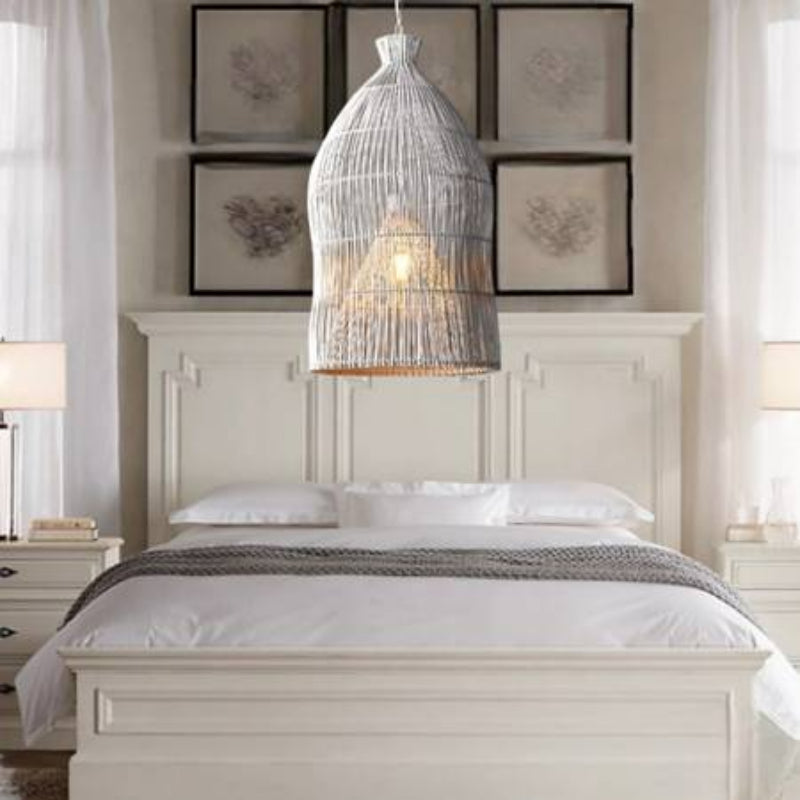 White rattan cage pendant suspended above a bed