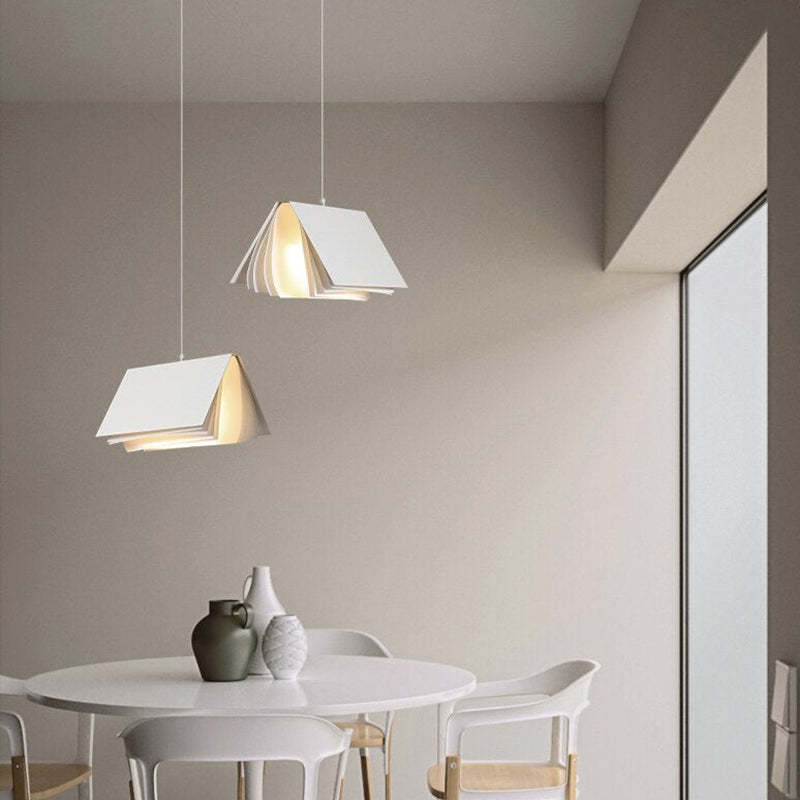 Two separate White Sienna book-style pendants at different heights above a round white table with vases and white chairs