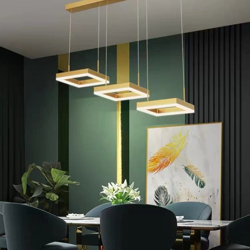 Raheel gold square pendant in a green-walled dining room.