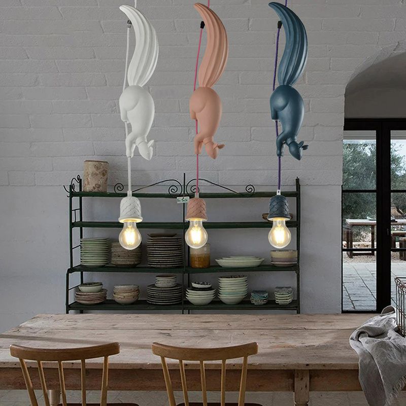 White, pink and blue squirrel pendants above a wooden dining table, with dish shelves and chairs