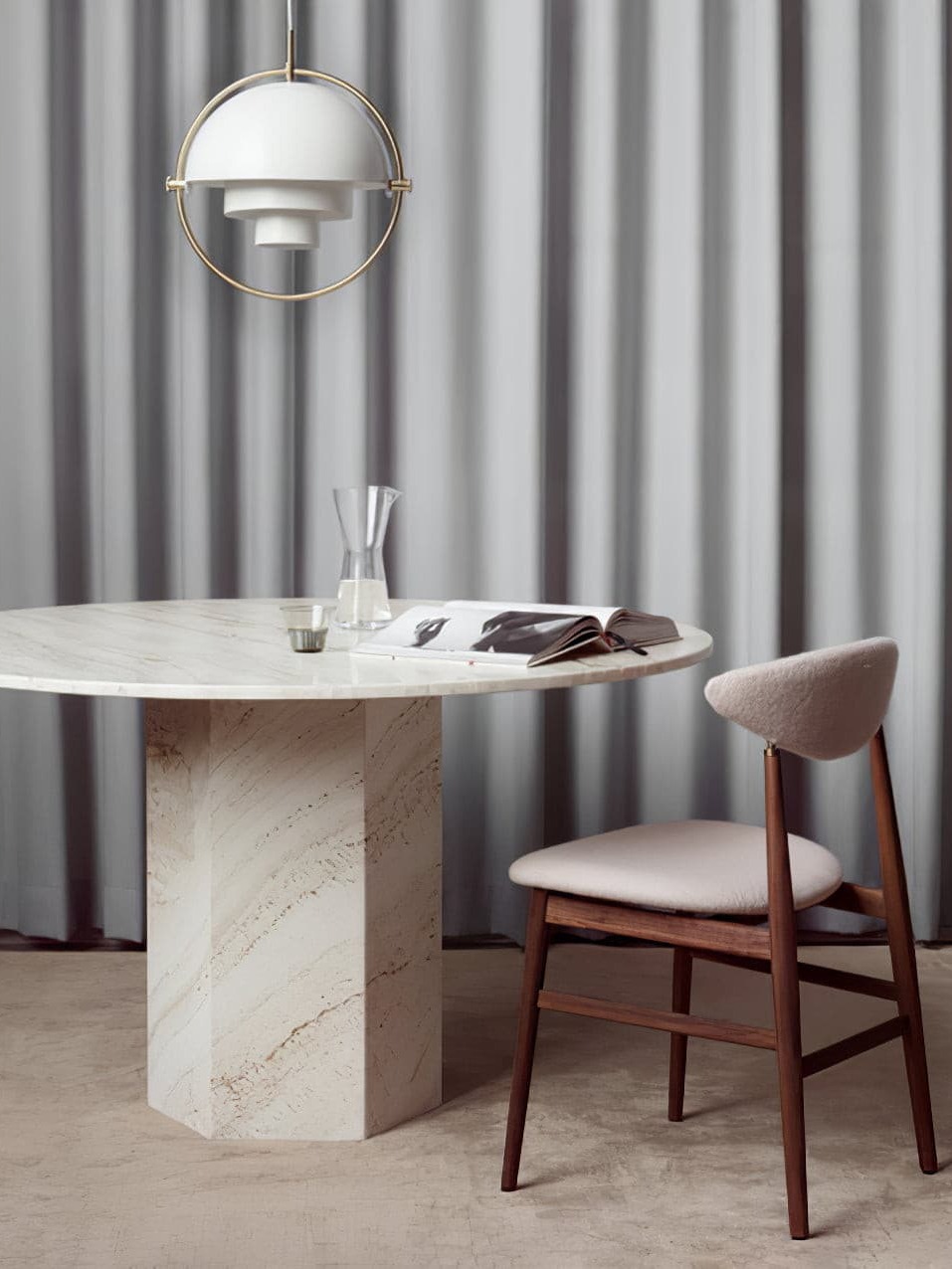 White pendant with a circular metal frame above a stone table