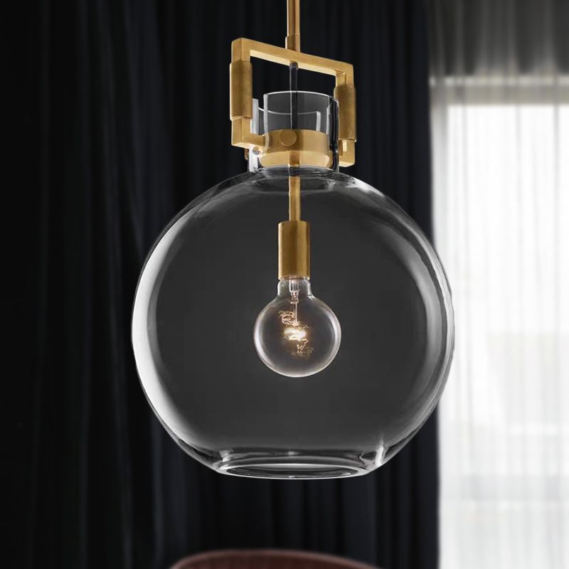 Cairns clear globe shade and brass-colour neck frame with a visible bulb before dark curtains
