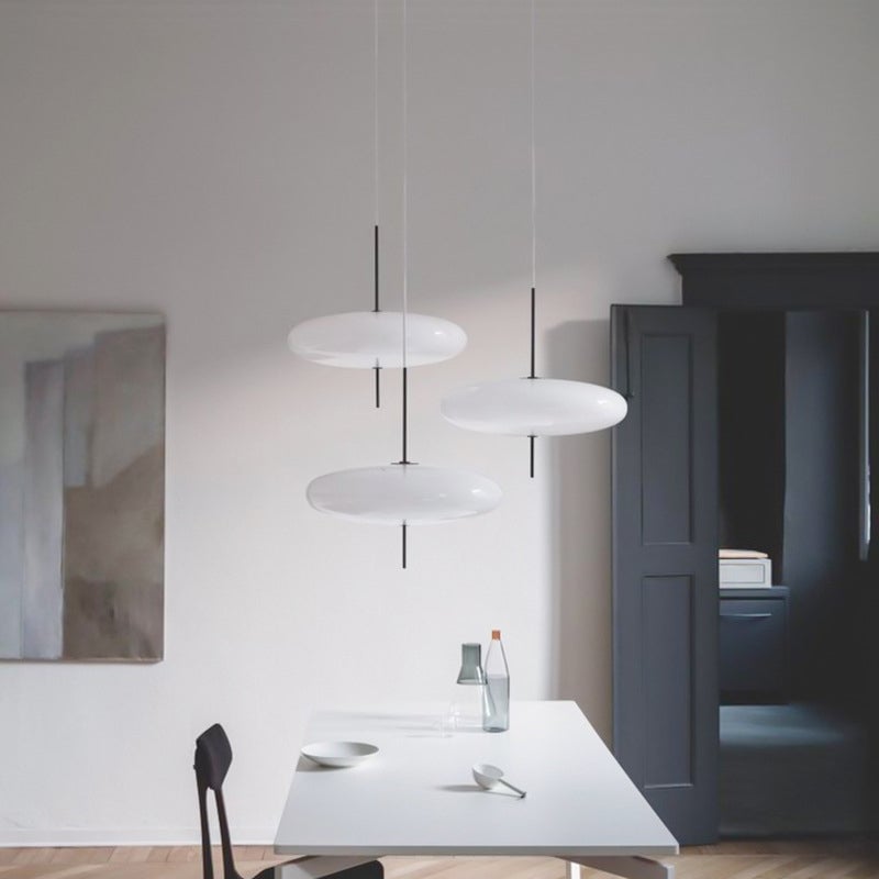 Three Leilani white oval pendants pictured above a white dining table