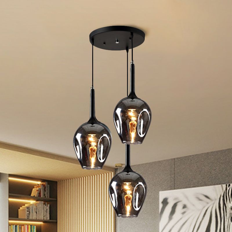 Smoke-gray glass cluster pendant with three darker reflective shades near a bookcase and horse artwork