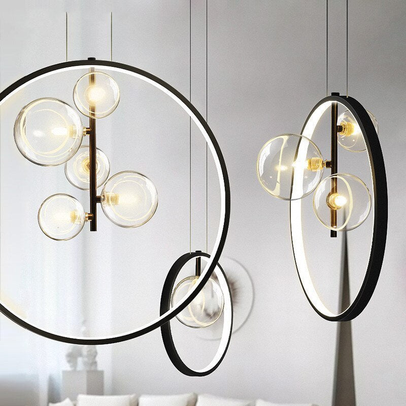 One-, three- and five-globe ring pendants at different angles against a pale wall above a sofa