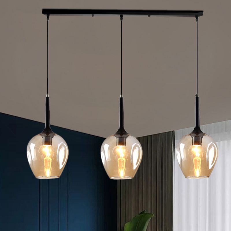 Hailie Amber glass pendant with three shades against a dark teal wall