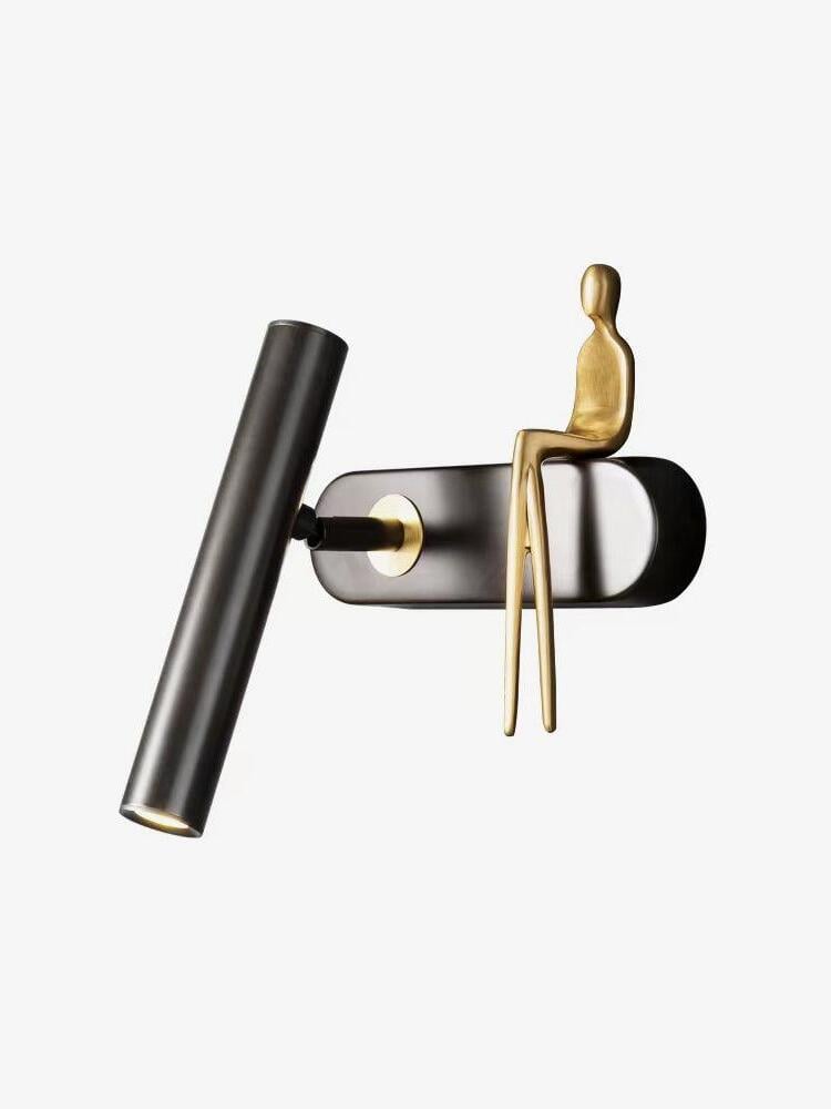 Single black wall light isolated on white with tilted tube on the left and seated gold figure on the right