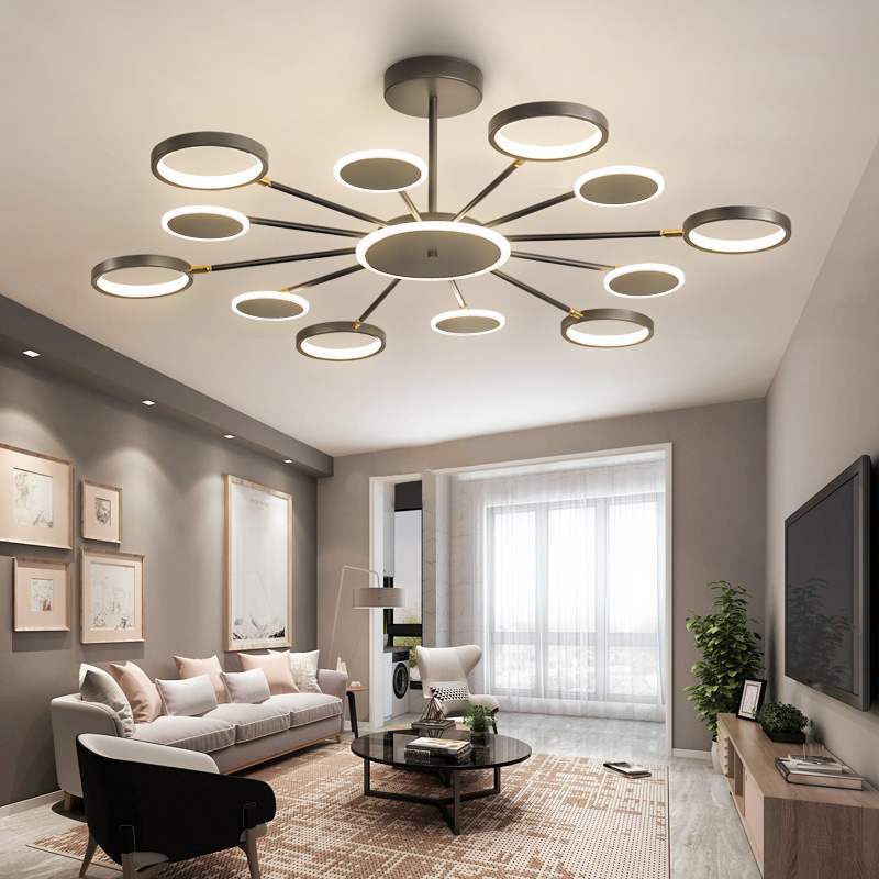 Twelve-arm ring and disc chandelier with flat heads above a living-room sofa, round table and TV