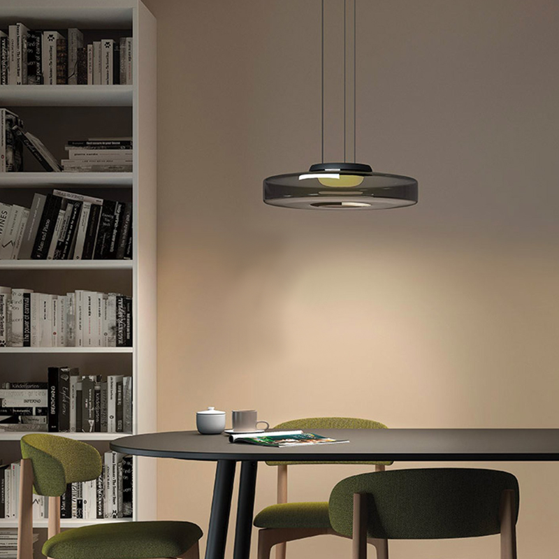 Smoke-grey disc pendant above table beside shelves