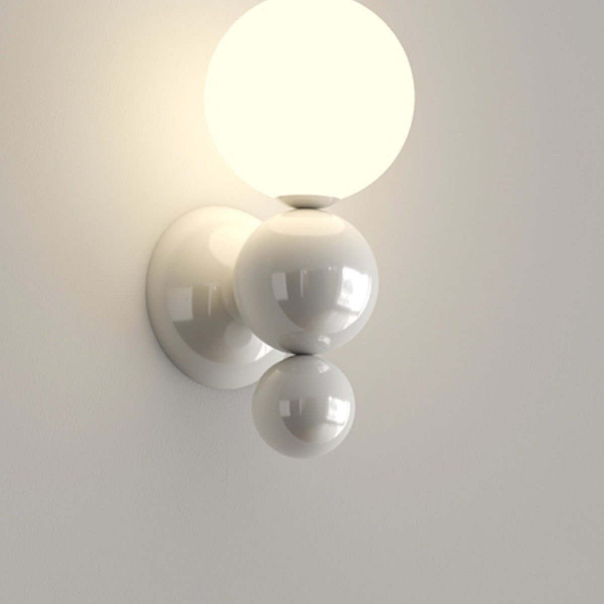 White Valentina wall light with stacked rounded elements and a glowing glass globe