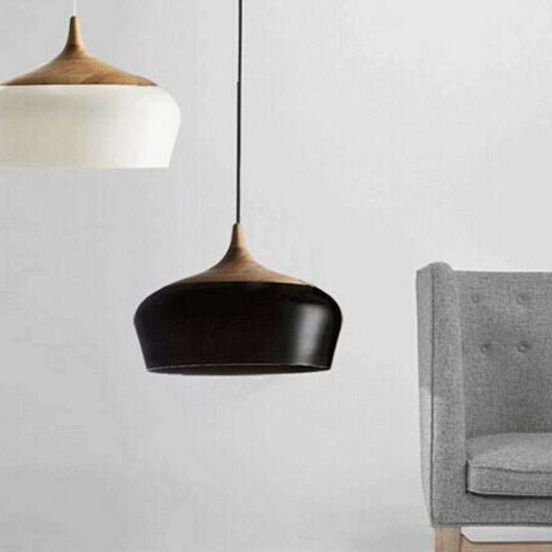 Black Nazifa pendant beside a grey upholstered chair, with a white shade partly visible.