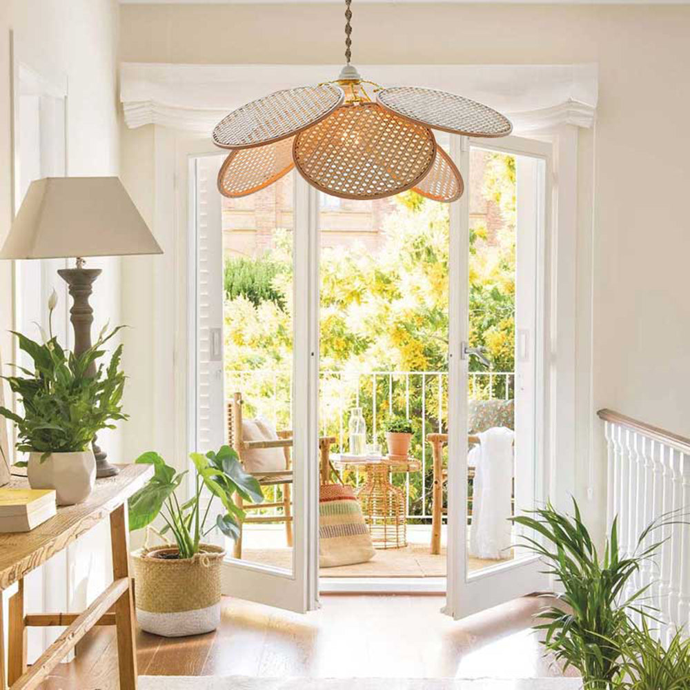 Single woven petal pendant in a bright indoor entry by open French doors, plants and a console lamp