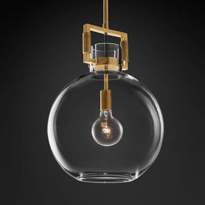 Close view of Cairns clear globe shade, brass-colour neck frame and bulb against a dark background
