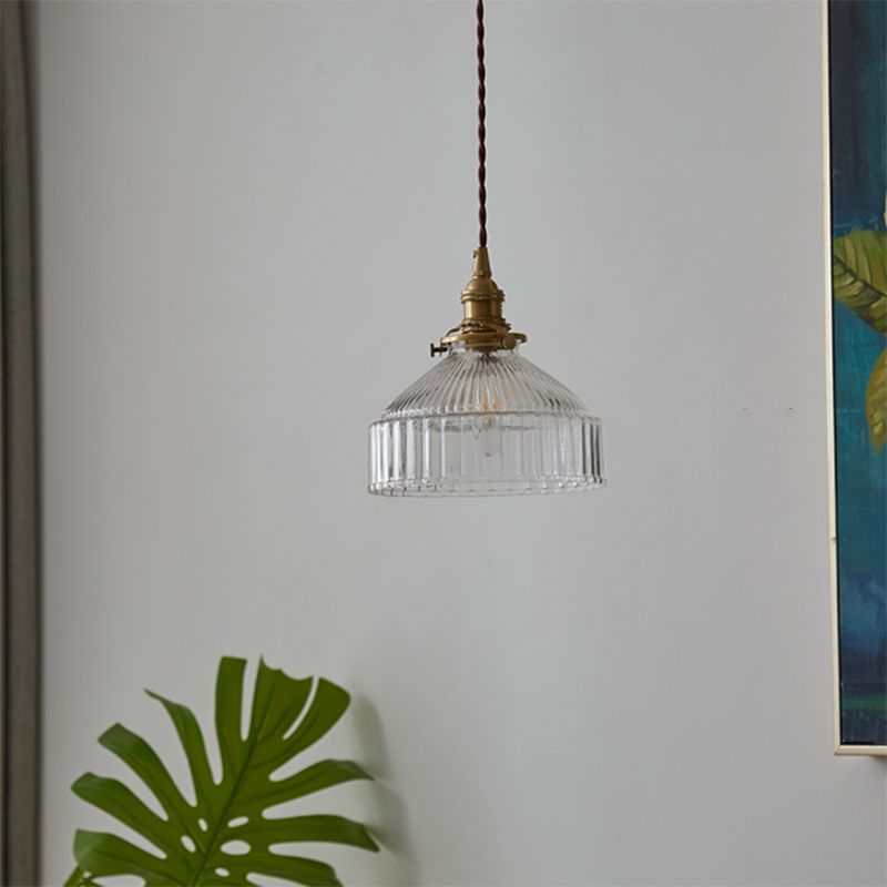 Cairns glass dome pendant with vertically ribbed shade beside indoor foliage