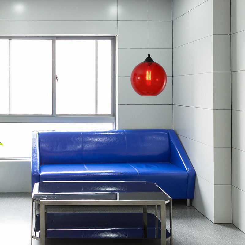 Red glass globe pendant in room with blue sofa