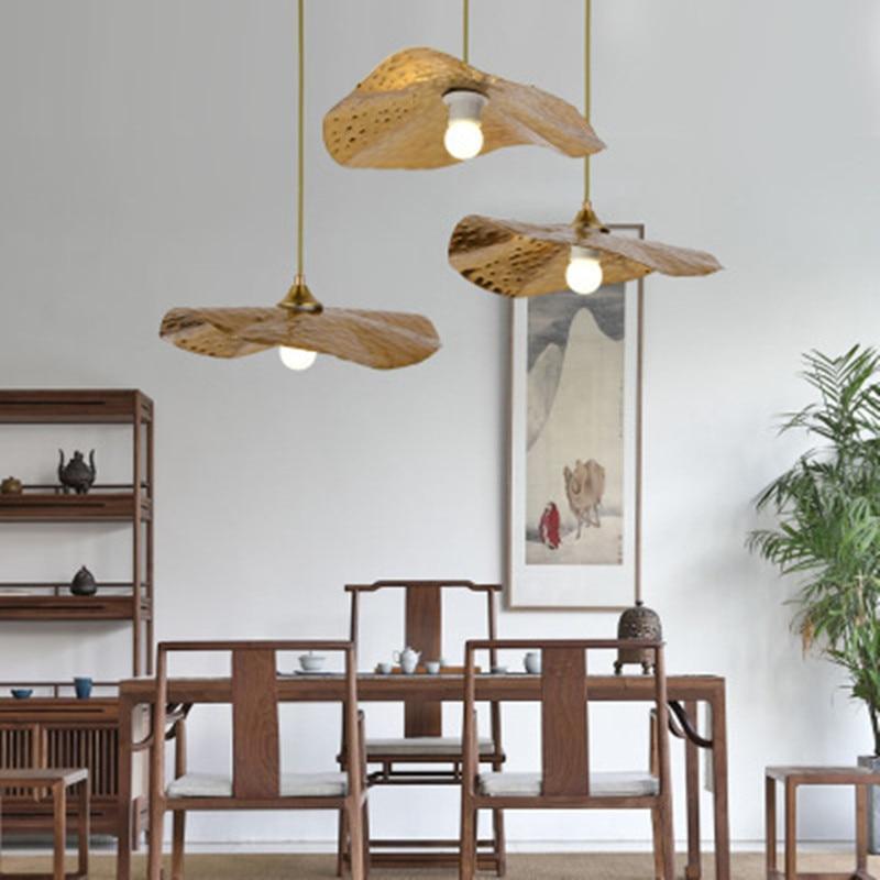 Three gold-tone lotus leaf pendants at varied heights in a furnished room
