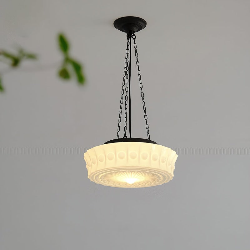 Warmly lit pale glass pendant against grey wall