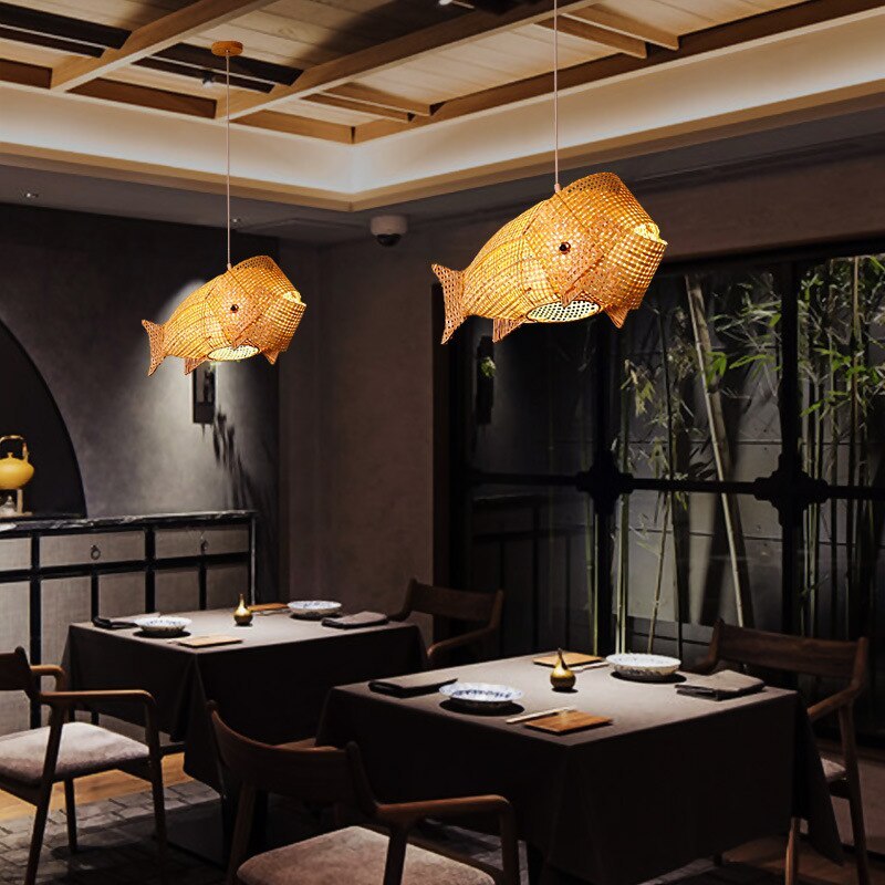 Two illuminated Muto fish pendants above restaurant tables