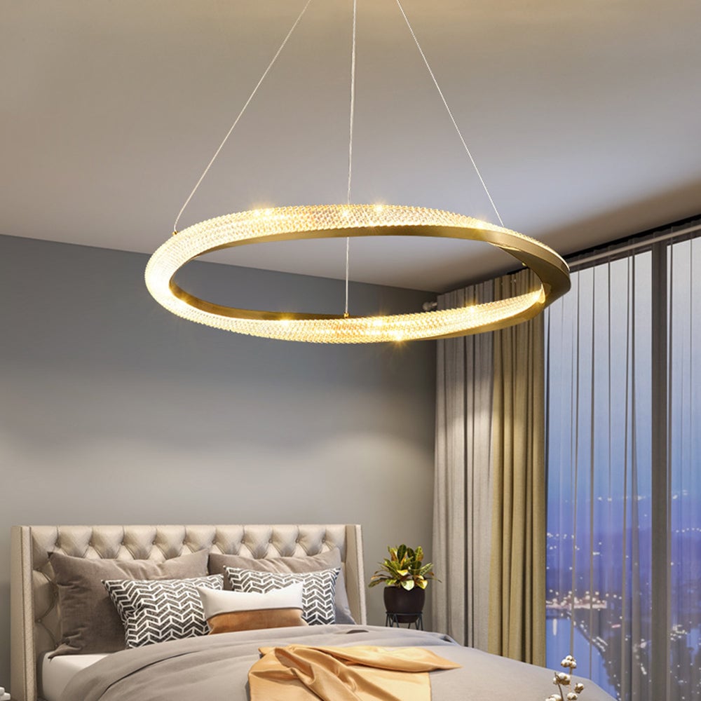 Gold single-ring pendant above a bed with a tufted pale headboard beside a window