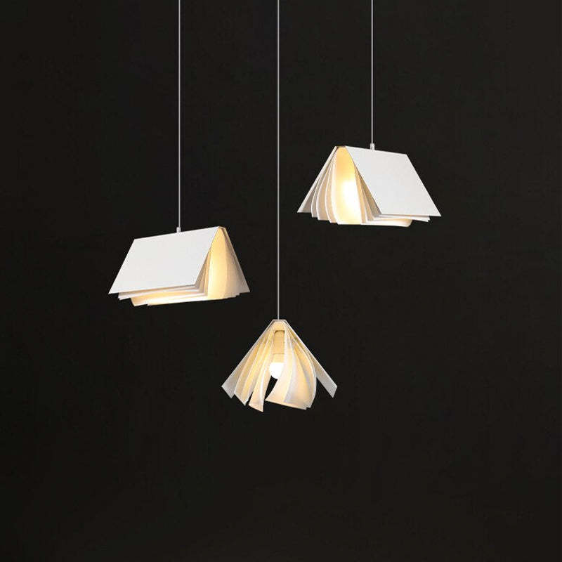 Three separate White Sienna layered book-style shades illuminated against black, with the central light visible from below