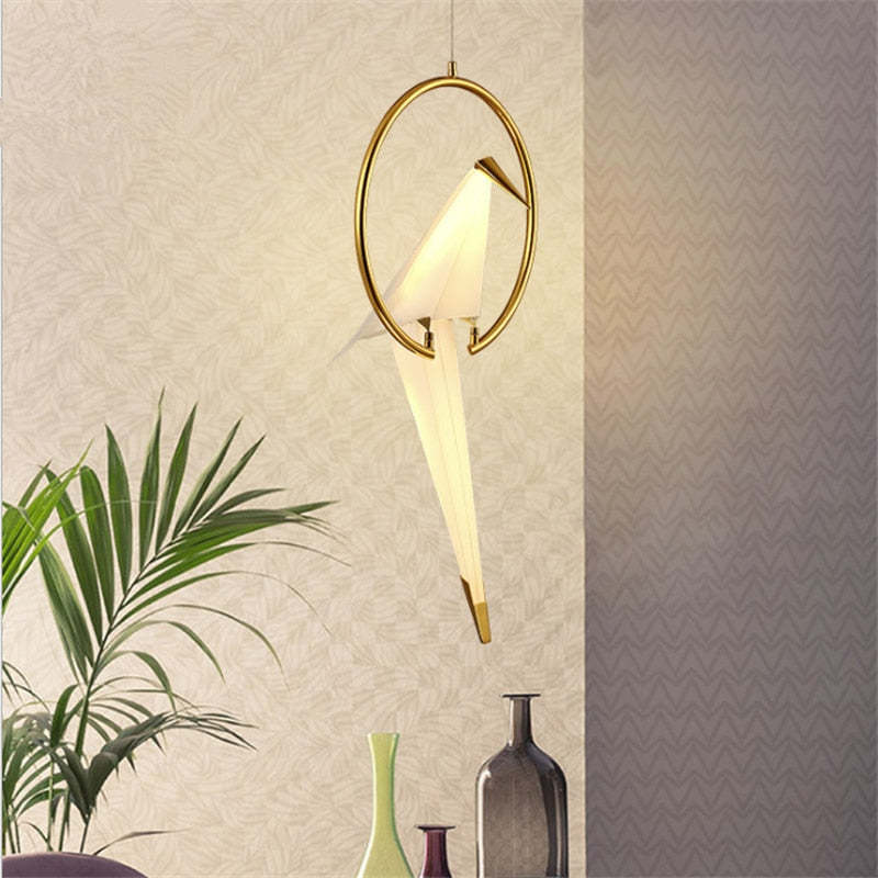 Single-bird pendant glowing beside a plant and decorative vases.