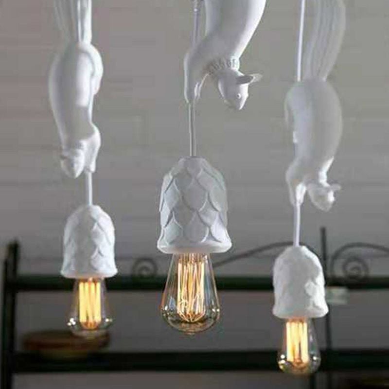 Three white squirrel pendants with pinecone-pattern holders and long exposed bulbs above furniture