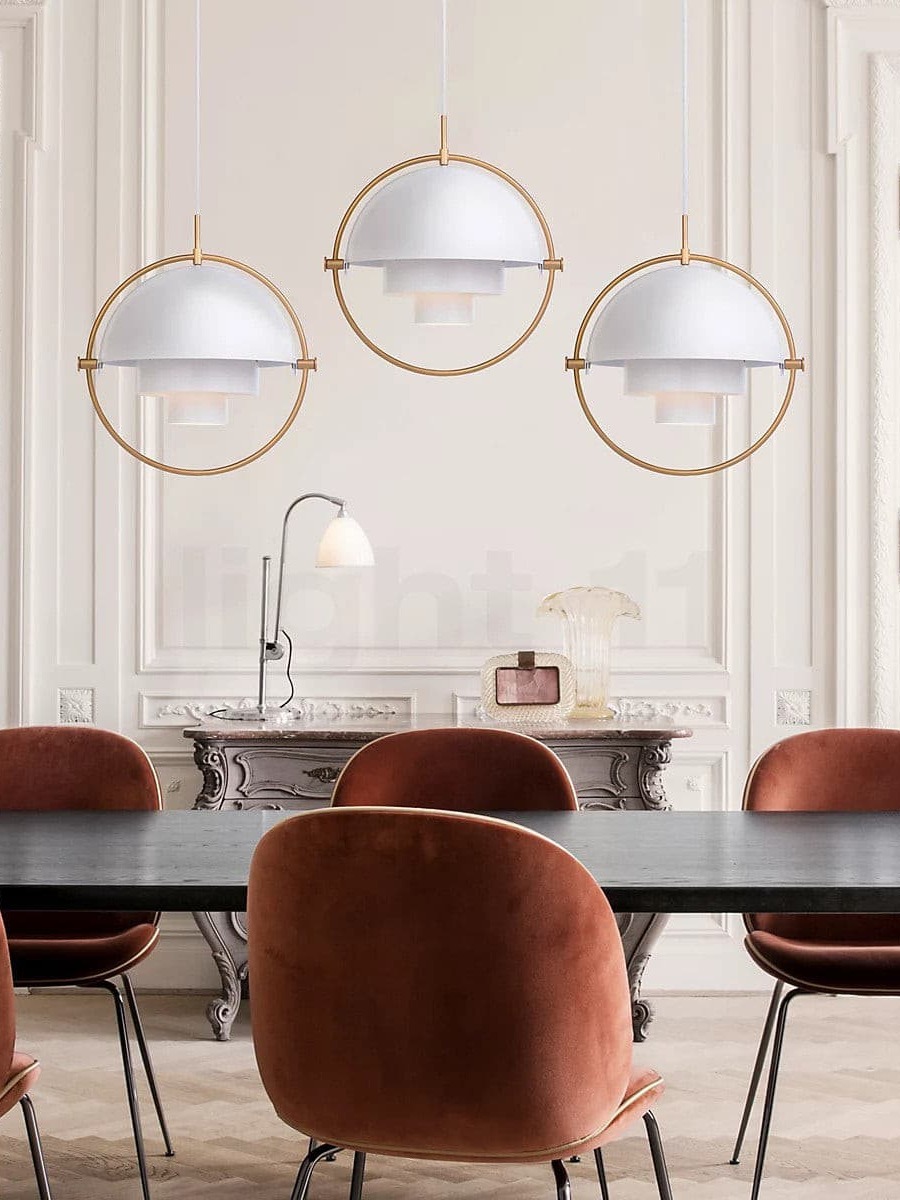 Three white and copper-coloured pendants above dining seating