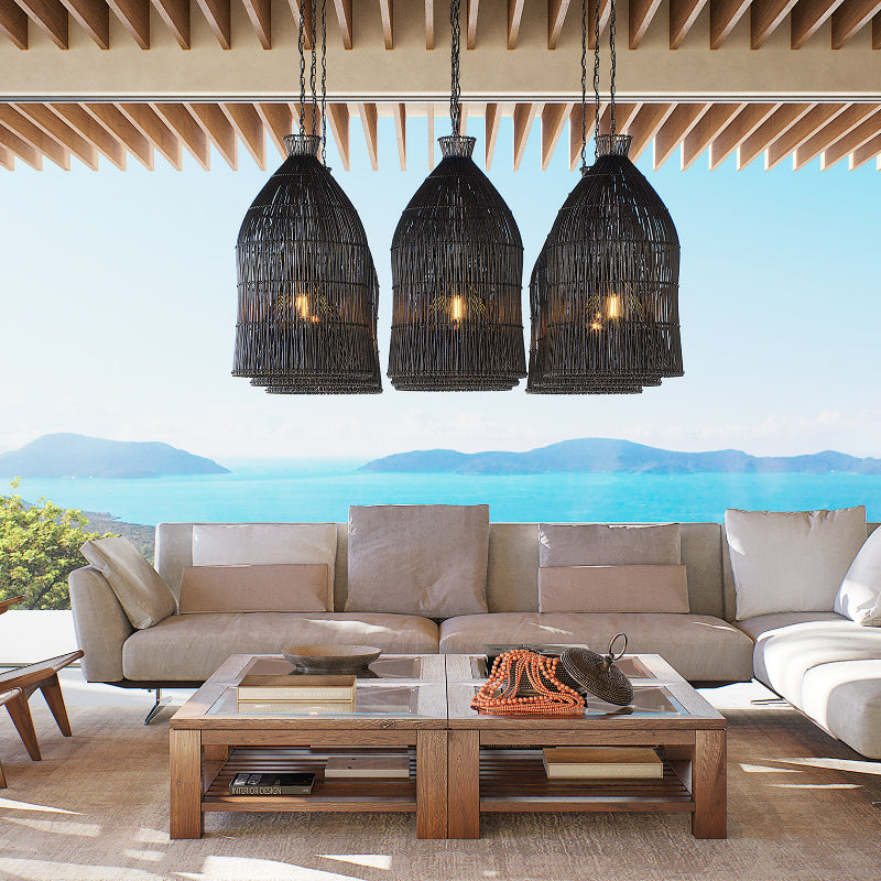 Three black rattan cage pendants hanging above a sofa