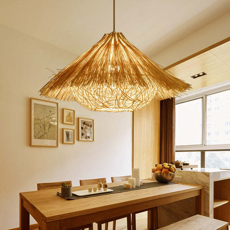 Illuminated Muto woven rattan pendant above a wooden dining table beside windows.
