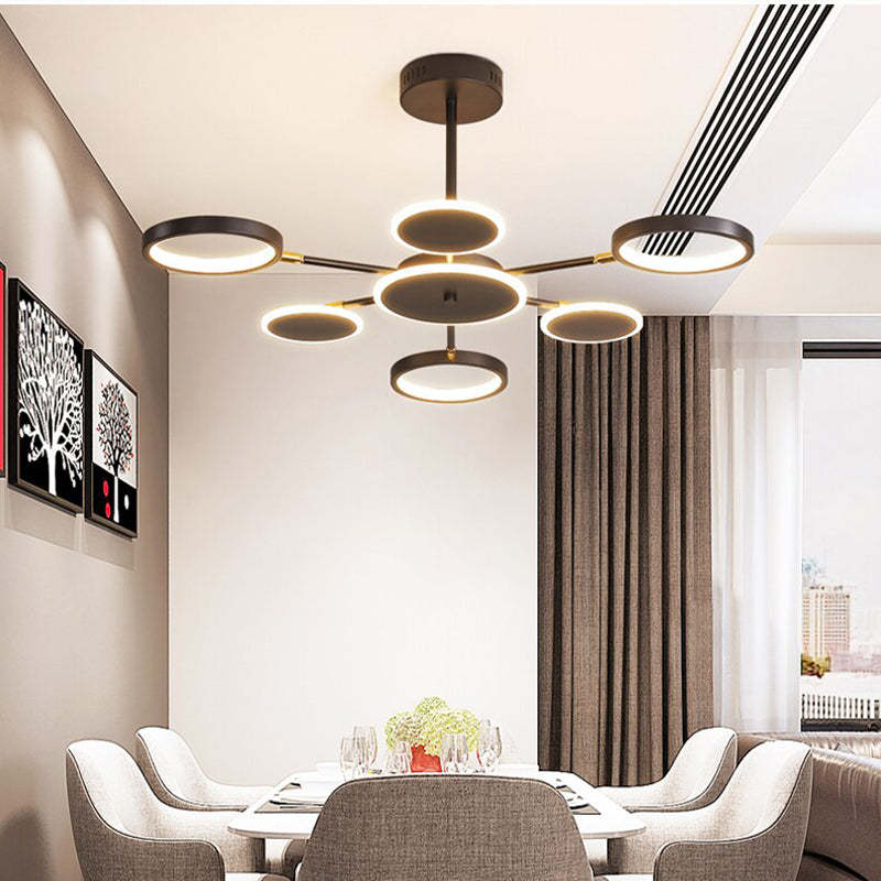 Six-arm ring and disc LED chandelier above an indoor dining table and upholstered chairs