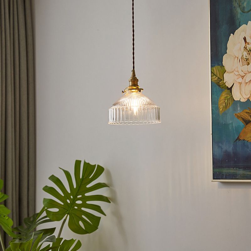 Cairns Brass variant glass pendant hanging beside curtains and foliage