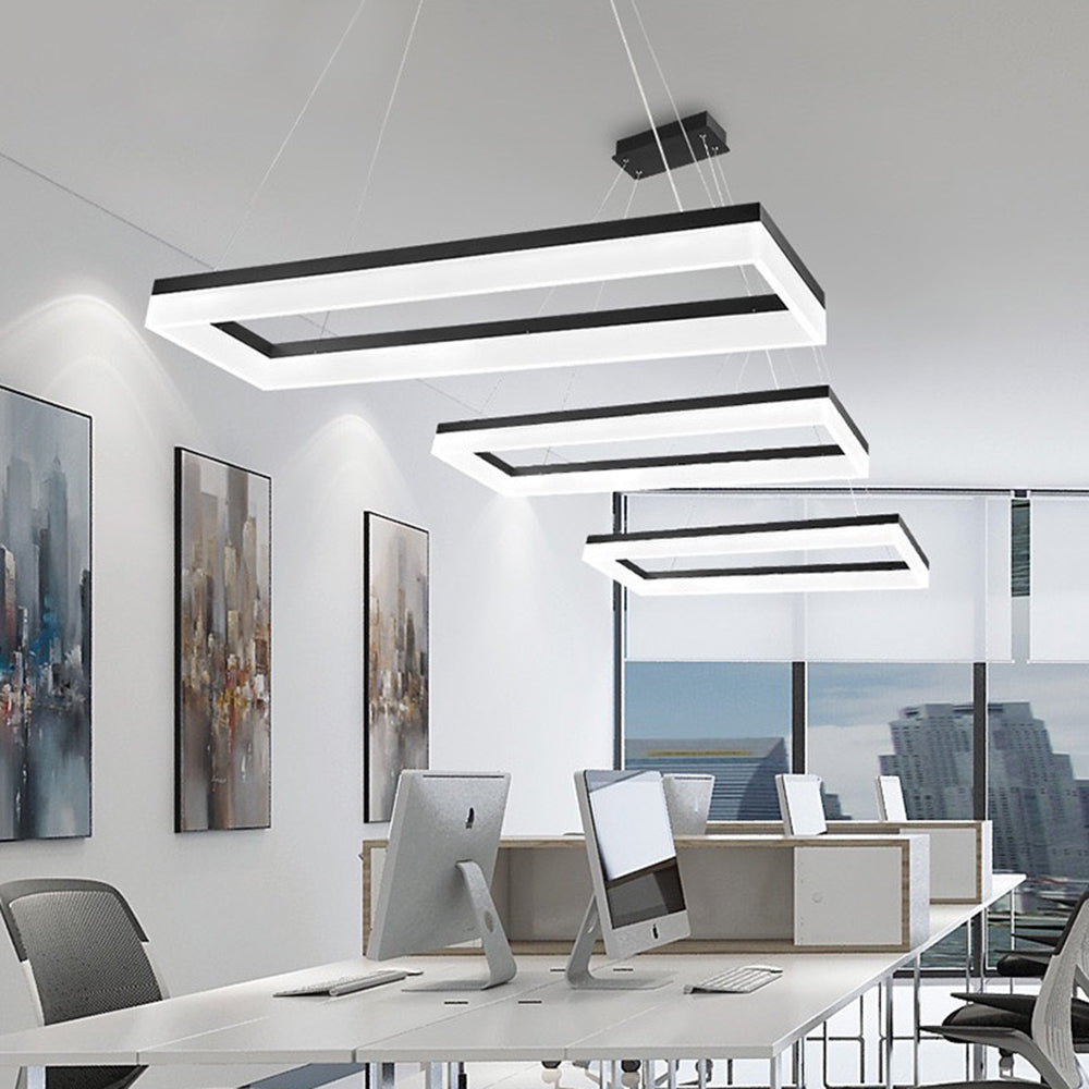 Three Bouvet rectangular pendants above a row of office desks with computers, white keyboards, city artwork and a window city view.