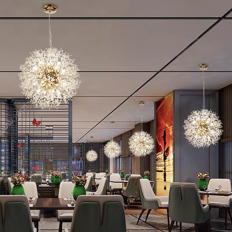 Gold dandelion pendants above dining tables with upholstered chairs, green plants and colourful mural