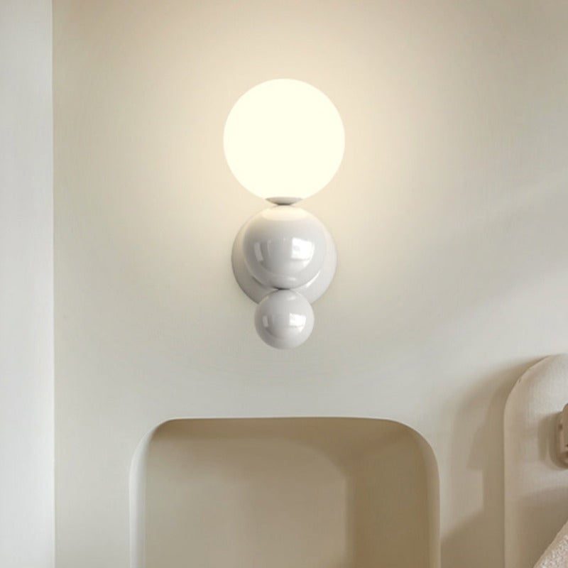White Valentina globe wall light above a cream headboard