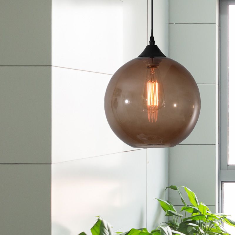 Coffee tinted glass globe pendant beside window and plants