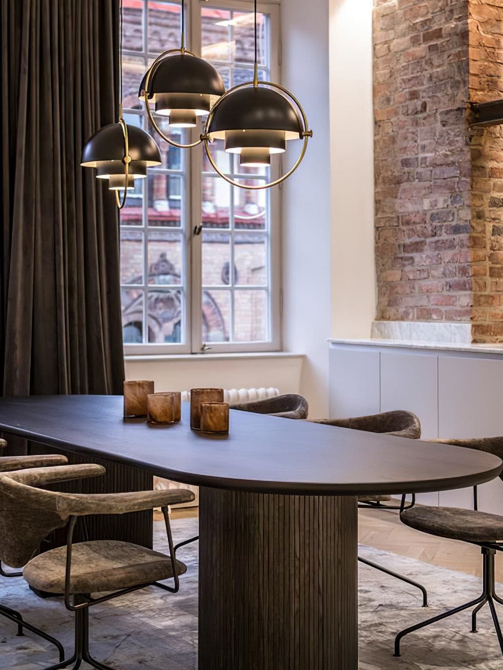 Three dark metal pendants above a wooden dining table