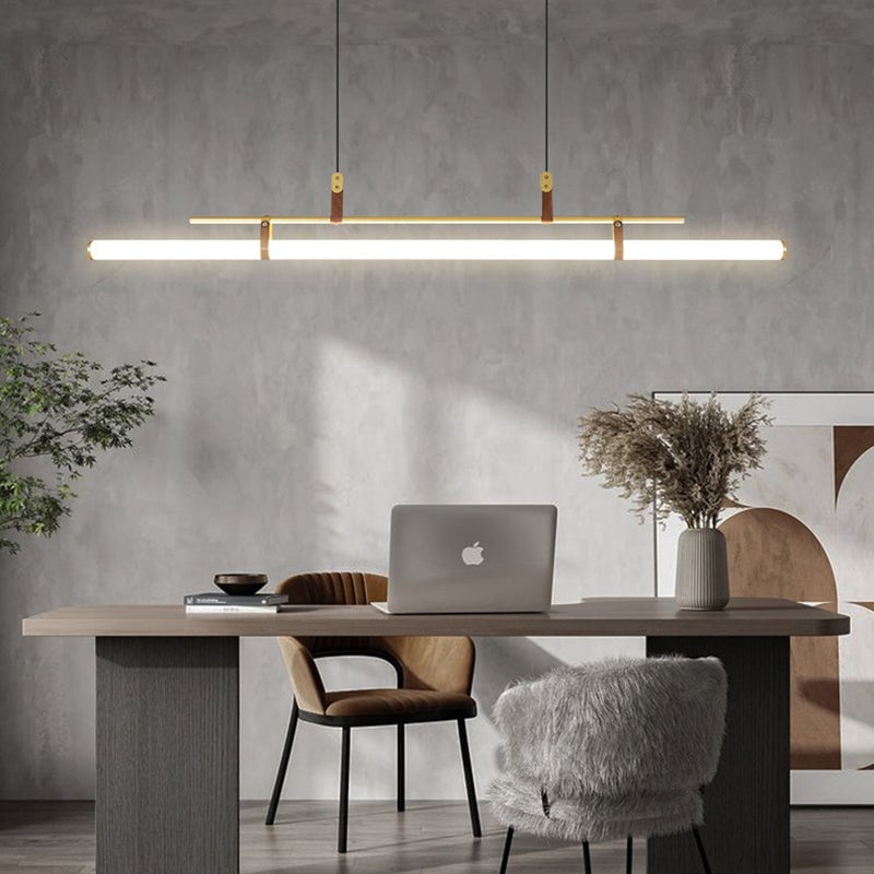 Gold linear pendant above a wooden desk with a laptop and dried flowers, brown chair and gray furry stool