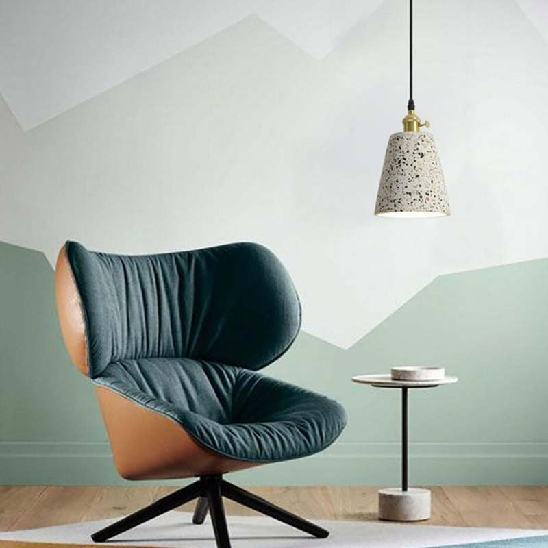 Short speckled cone pendant with gold-tone holder beside a dark chair and small side table