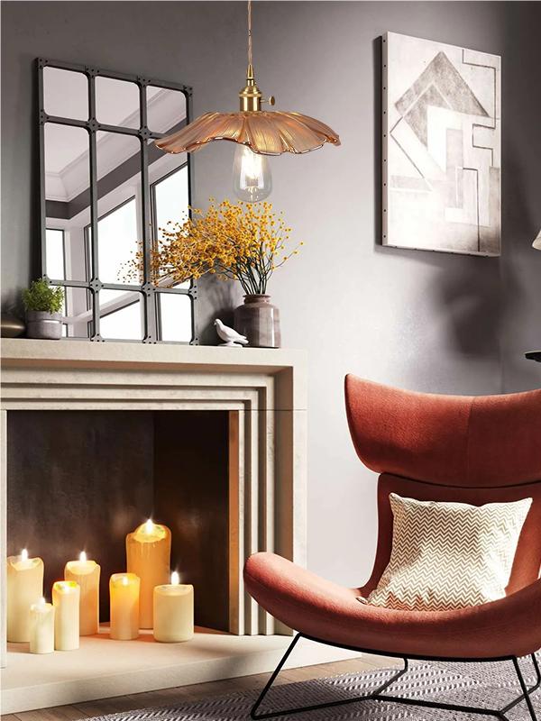Illuminated amber lotus pendant beside a fireplace