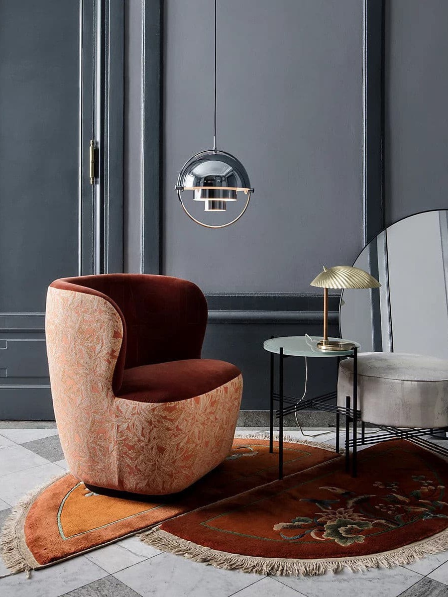 Chrome-finish pendant beside a rust-coloured chair