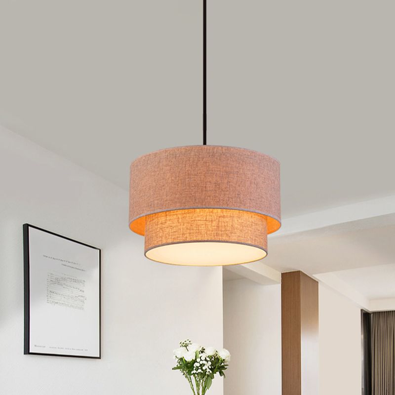 Flaxen-colour Renee dual-drum pendant illuminated above a tabletop.