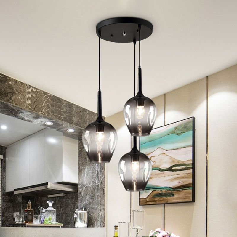 Gray glass cluster pendant above a bar area with bottles, flowers, framed art and a marble wall