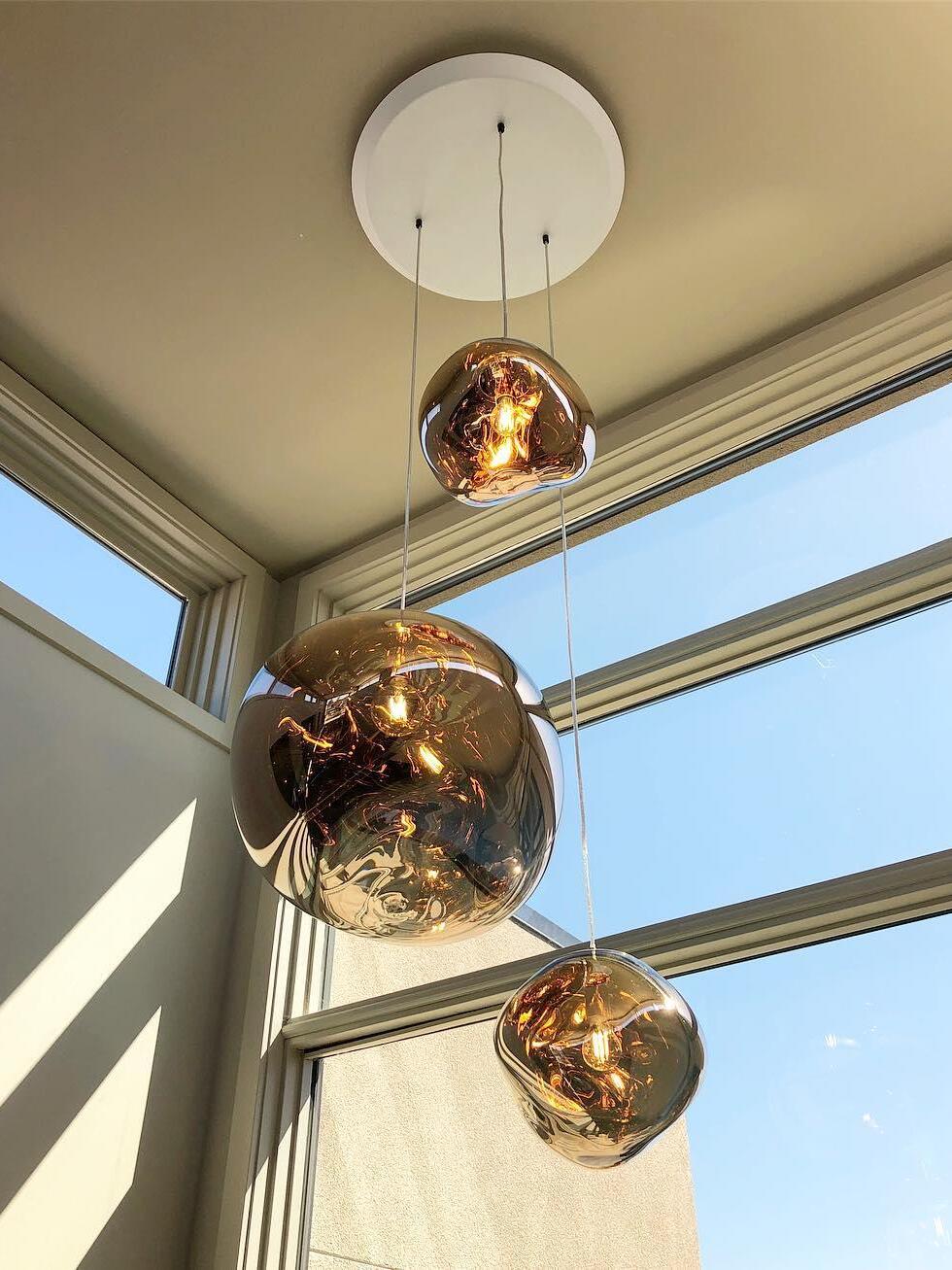 Three gold-toned shades beneath a round shared canopy