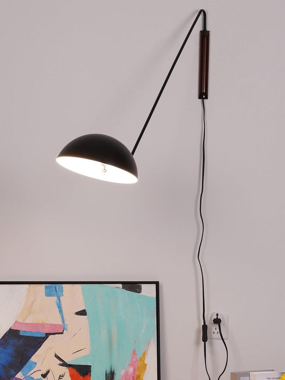 Lit black dome at the end of a long arm, with dark wooden mount and hanging switched cable connected to an outlet