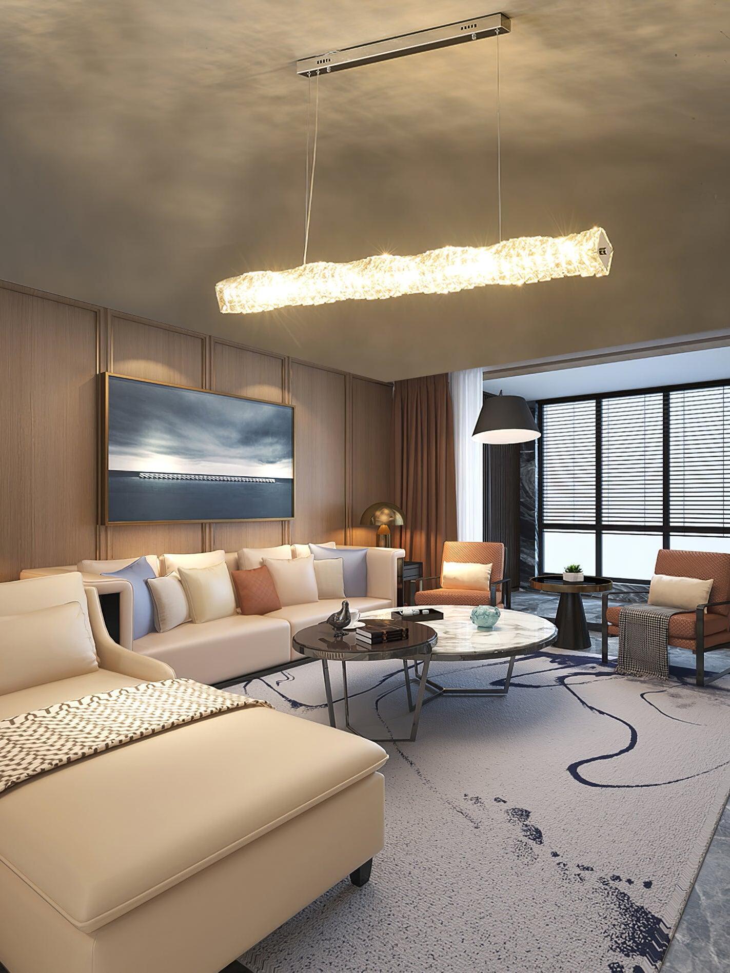 Warm-looking crystal pendant above circular coffee tables in a living room with pale sectional seating