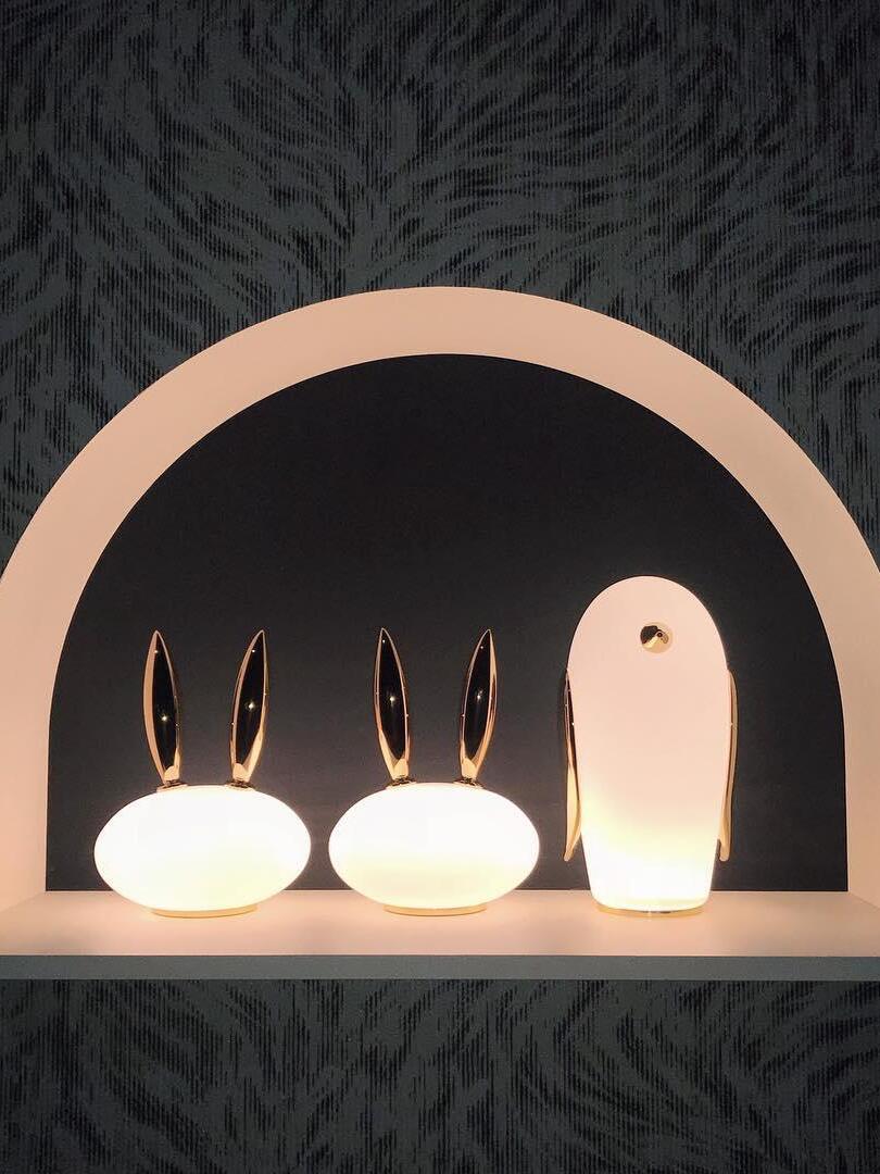 Two glowing rabbits and penguin under large arch in patterned room