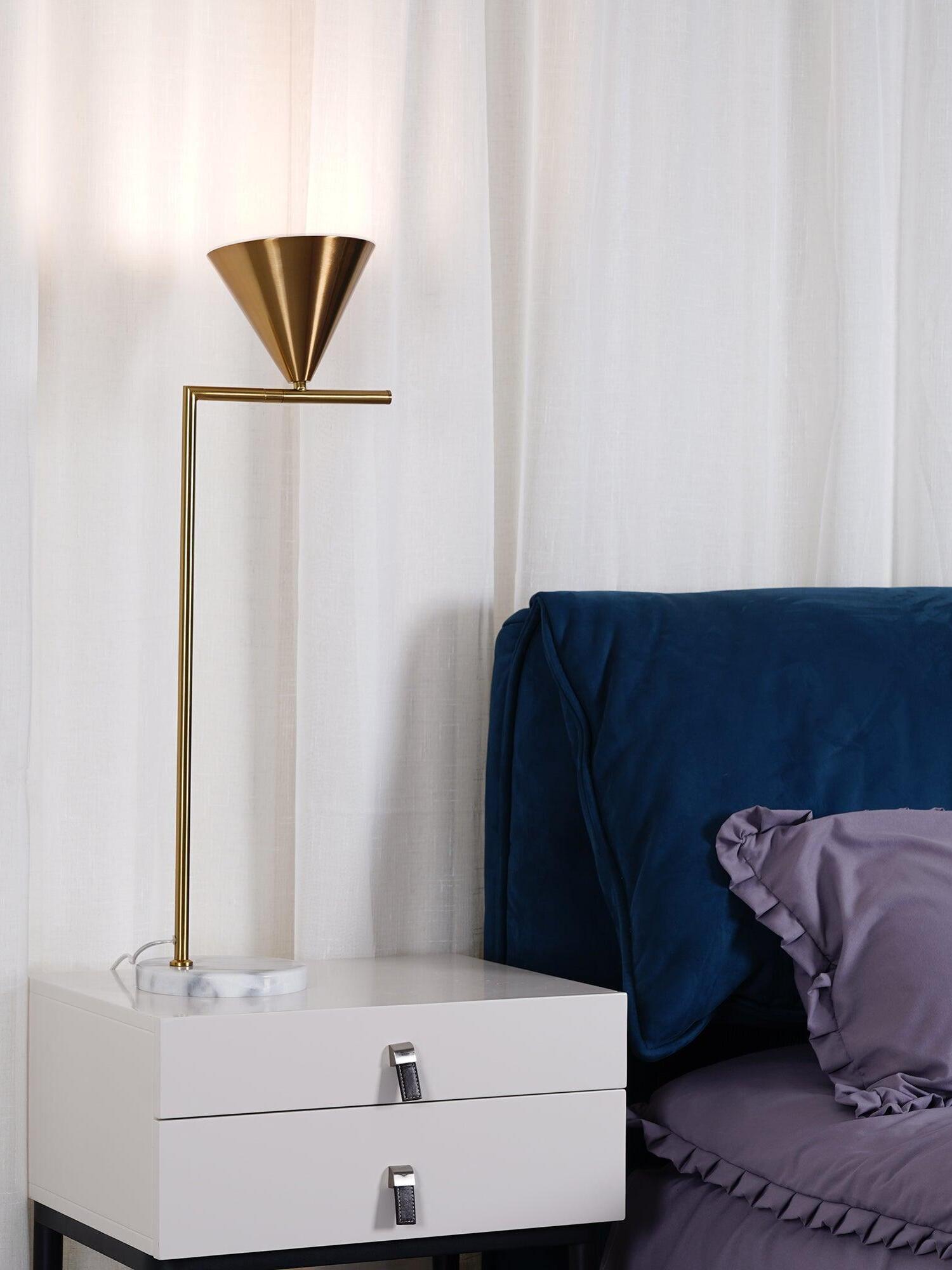 Cone shade turned upward beside blue upholstered bed