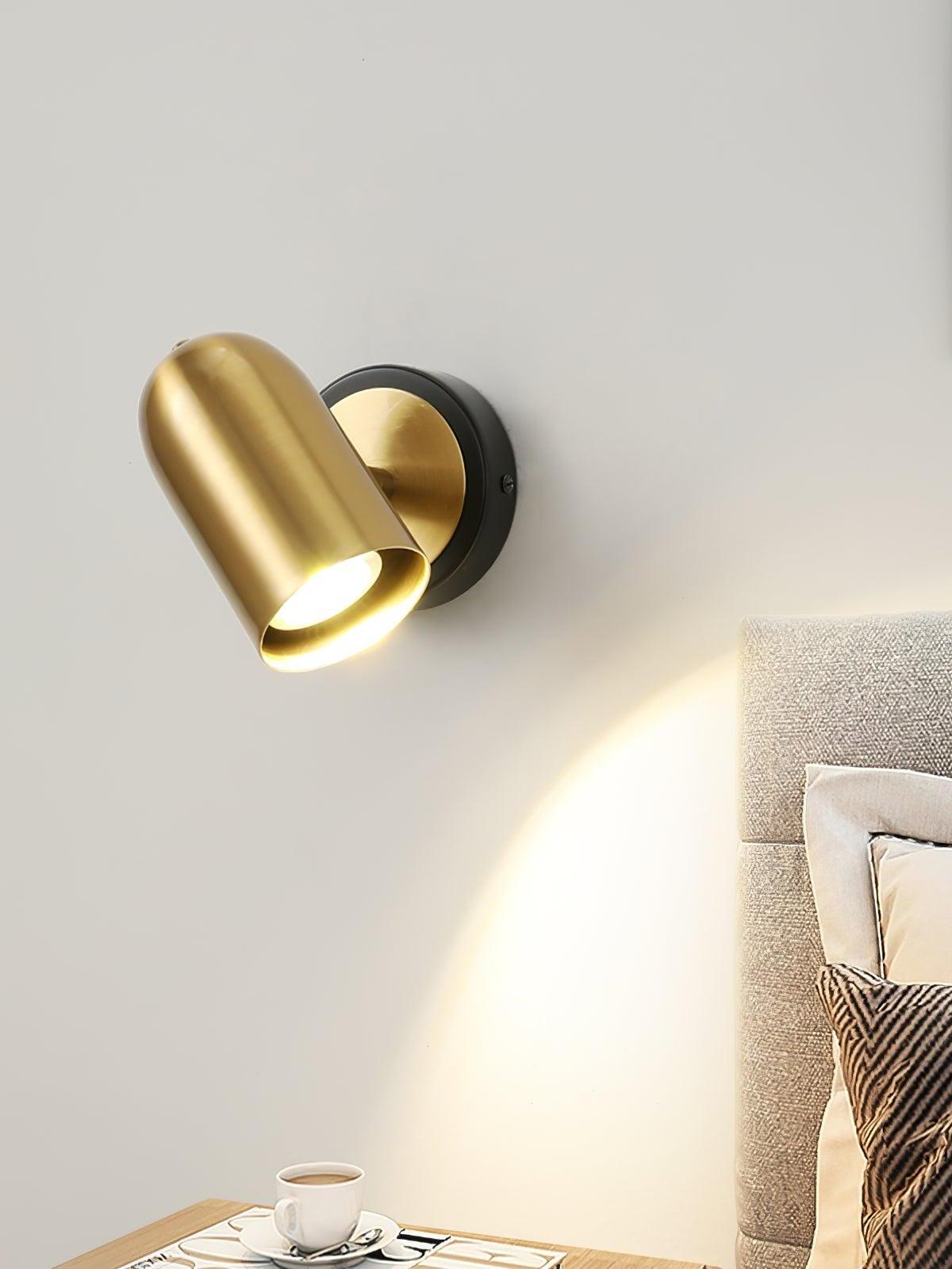 Gold wall lamp angled beside upholstered bed